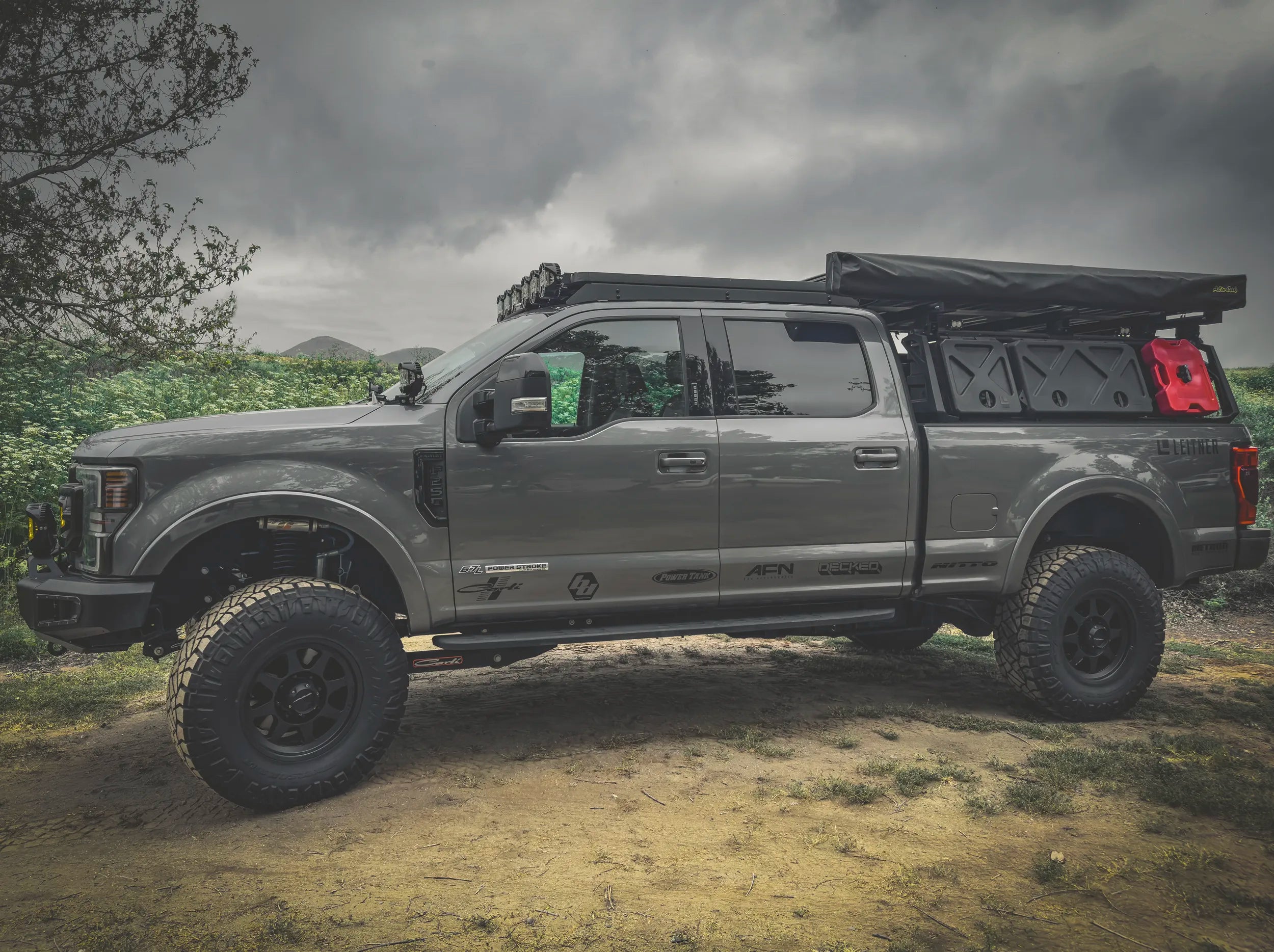 SIDE VIEW OF FORD SUPERDUTY WITH ACS ROOF RACK INSTALLED ALONG WITH ACS FORGED BED RACK WITH A GEARPOD, GEARPPOD DUAL AND ROTOPAX MOUNTED