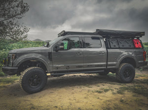 SIDE VIEW OF FORD SUPERDUTY WITH ACS ROOF RACK INSTALLED ALONG WITH ACS FORGED BED RACK WITH A GEARPOD, GEARPPOD DUAL AND ROTOPAX MOUNTED