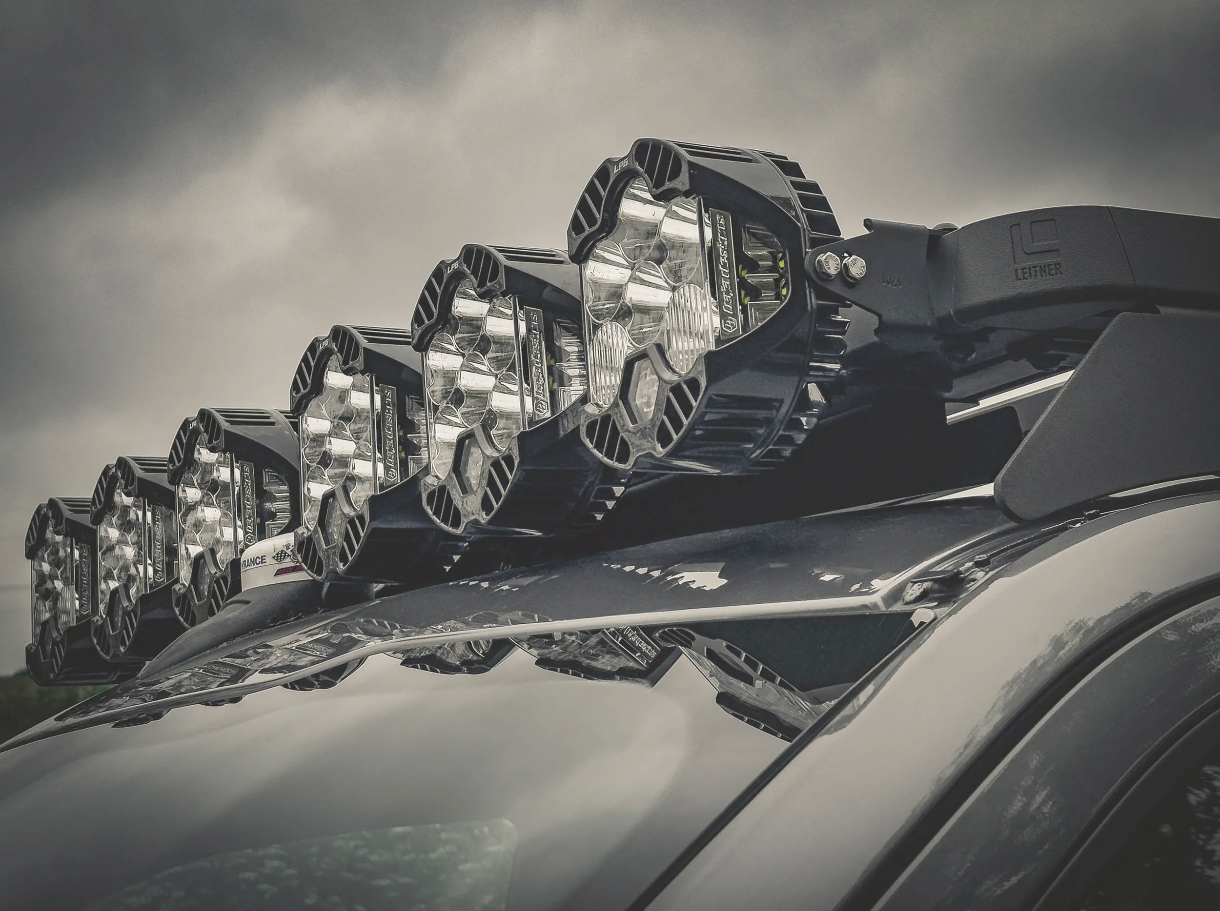 CLOSE UP VIEW OF LIGHTS ATTACHED TO ACS ROOF RACK SHOWING CORNER CAP WITH LEITNER LOGO 