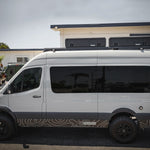 SIDE VIEW OF WHITE SPRINTER BUS AND 2 GEARPOD ROOFS MOUNTED ON ROOF RACK